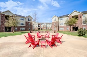 Red Adirondack chairs surrounding fire pit exterior at Mustang Village in Wichita Falls Student Accommodation