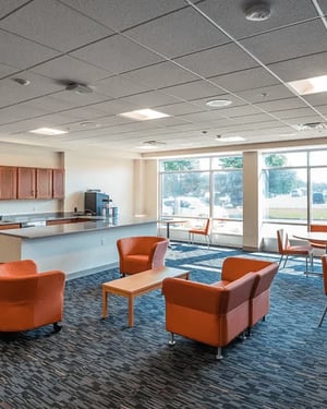 Orange chairs coffee table kitchen counter lounge area at Campus Walk Apartments in Buffalo Student Accommodation