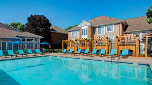 Blue lounge chairs and umbrellas poolside exterior at Campus Court At Knollwood in Kalamazoo Student Accommodation