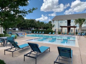 Pool with lounge chairs and buildings exterior at Angelo Place Apartments in San Angelo Student Accommodation