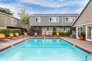 Pool with lounge chairs outside apartment buildings exterior at Connery Place Apartments in Portland Student Accommodation