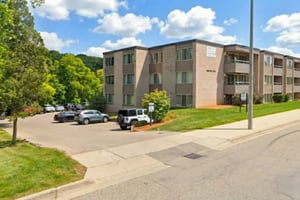 Apartment building with cars and trees exterior at Americana Apartments in East Lansing Student Accommodation