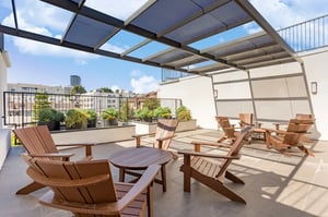 Wooden chairs and tables on a patio exterior at 1025 Berendo Villas in Los Angeles Student Accommodation