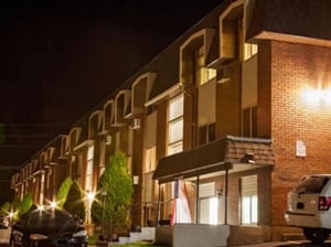 Brick building with cars and trees exterior at Bridgerland Apartments in Logan Student Accommodation