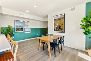 Wooden table with chairs artworks and plants communal area at Ascent at Campus of Life in San Diego Student Accommodation