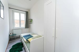 Bed with green rug and white wardrobe bedroom at Sterndamm 83.4 in Berlin Student Accommodation
