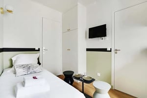 Bed towels television cabinets and doors bedroom at Studio in 103 Rue Brancion, 75015 Paris, France in Paris Student Accommodation