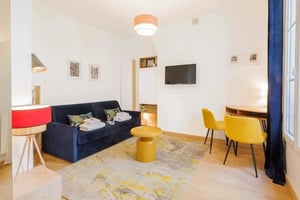 Dark blue couch yellow chairs abstract rug living room at Studio in 16 Rue Vieille-du-Temple, 75004 Paris, France in Paris Student Accommodation