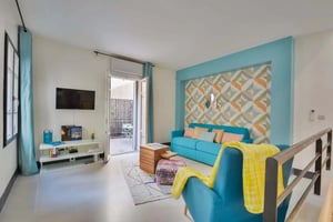 Blue sofa patterned wall television and chairs living room at Apartment in 3 Rue Tardieu, 75018 Paris, France in Paris Student Accommodation