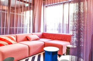 Pink sectional sofa striped pillows two tables living room at Vita Student Iona Street in Edinburgh Student Accommodation