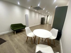 Green sofa white table chairs refrigerator living area at E7 8PF, Shaftsbury Rd, London in London Student Accommodation