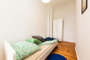 Bed with pillows wardrobe and wooden floor bedroom at Room in Buschkrugallee, 12359 Berlin-Bezirk Neukölln, Germany in Berlin Student Accommodation