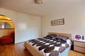 Bed with patterned duvet beside red sofa bedroom at Apartment in Rue Championnet, 75018 Paris, France in Paris Student Accommodation