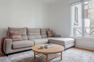 Beige sectional sofa coffee table patterned rug living room at Rue le Marois in Paris Student Accommodation