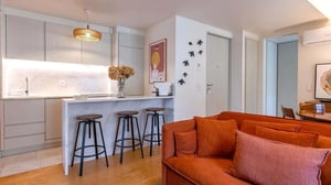 Kitchen island with bar stools and sofa living area at Graça Deluxe w/ City View Balcony in Lisbon Student Accommodation