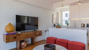 Television wooden cabinet art vase red ottomans living room at Design 3BDR Duplex W/Balcony in Lisbon Student Accommodation