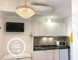 Chandelier television white cabinets microwave kitchen area at Studio with private terrace in Estrela, Lisbon in Lisbon Student Accommodation