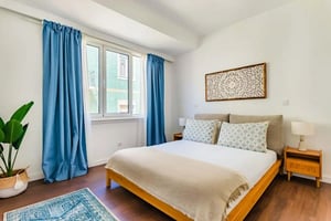 Bed with patterned pillows and blue curtains bedroom at Rua Cidade de Cardiff in Lisbon Student Accommodation