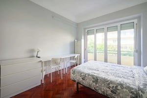 Bed dresser desk chairs balcony windows bedroom at Casa Elias VIII - Room 1 (with balcony) in Lisbon Student Accommodation