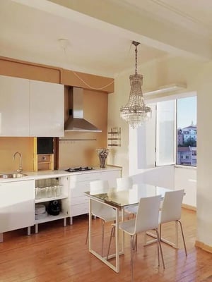 Kitchen with white cabinets dining table and chandelier Kitchen at Apartment in Rua da Bela Vista à Graça, Lisbon in Lisbon Student Accommodation