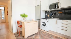 Folding table with orange chair washing machine and kitchen kitchen at Cozy studio apartment right at the centre of historical Lisbon (Baixa 2.) in Lisbon Student Accommodation
