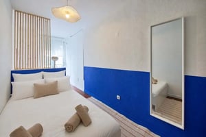 Bed with white linens blue wall mirror bedroom at Bedroom in a 3-bedroom apartment in Lisbon - Room 1 in Lisbon Student Accommodation
