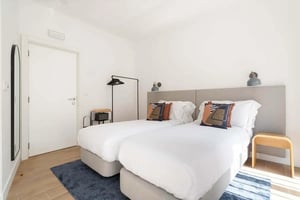 Two beds with patterned pillows coat rack bedroom at Lapa Diplomatic Suite 0.1 By Feel Lisboa in Lisbon Student Accommodation