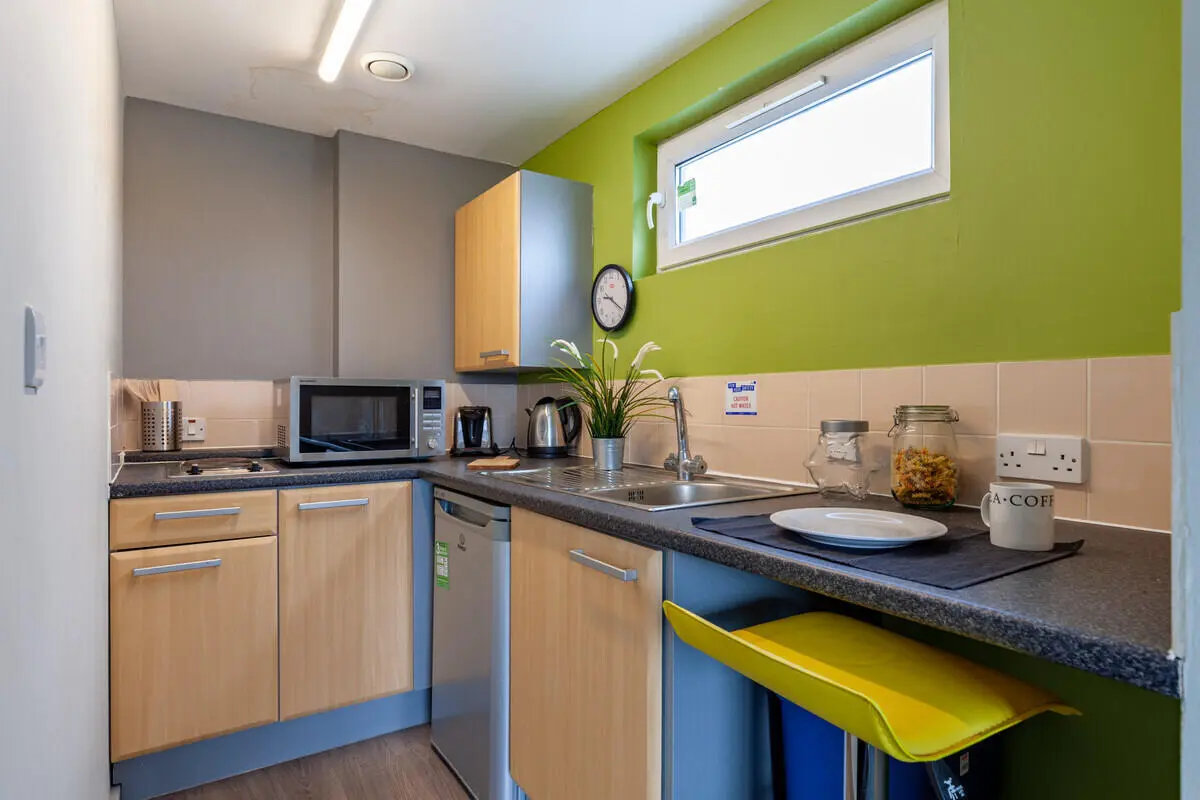 Microwave kettle sink cabinets yellow stool kitchen at Filbert Village in Leicester Student Accommodation