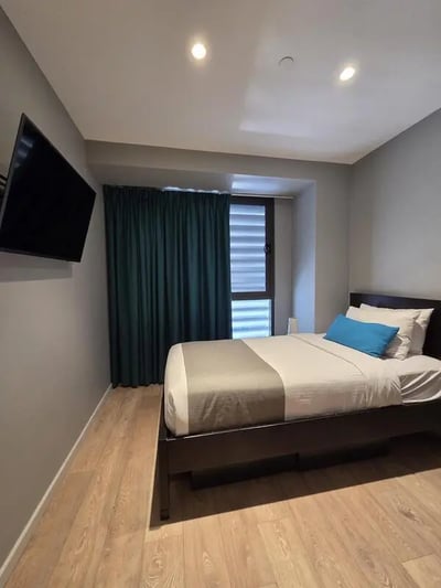 Bed with blue pillow TV on wall bedroom at Sydney Student Living Top Ryde in Sydney Student Accommodation