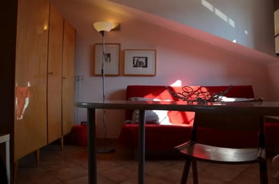 Red sofa framed pictures lamp and wardrobe living room at Bright studio close to Porta Palatina in Turin Student Accommodation