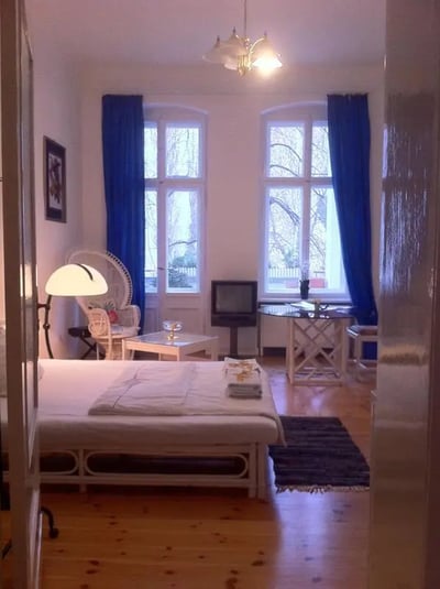 Bed armchair table television with blue curtains bedroom at Comfy double bedroom close to U Hohenzollernplatz metro station in Berlin Student Accommodation