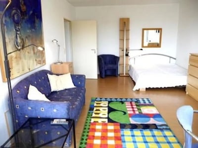 Blue sofa bed chair rug bright living room at Neat 2-bedroom flat in Schöneberg in Berlin Student Accommodation