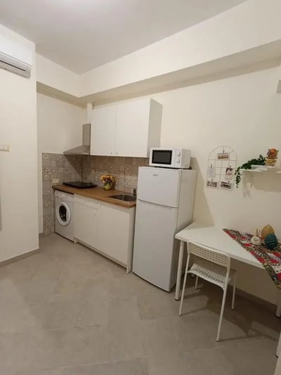 Small kitchen with white cabinets refrigerator and table Kitchen at Cozy studio very close to Università degli Studi di Palermo in Palermo Student Accommodation