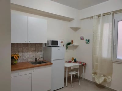 White cabinets microwave sink and table kitchen at Cozy studio very close to Università degli Studi di Palermo in Palermo Student Accommodation