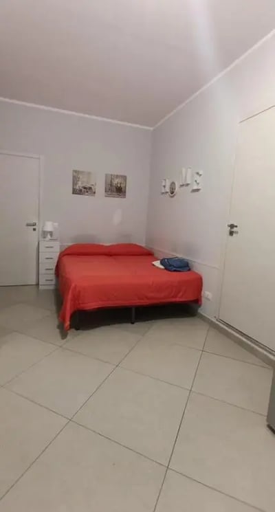 Red bed white dresser and art bedroom at Comfortable and bright Studio next to Stazione Centrale di Palermo in Palermo Student Accommodation