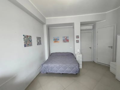 Bed bedside table artwork and doors bedroom at Cozy and comfortable studio next to Palermo's central station in Palermo Student Accommodation
