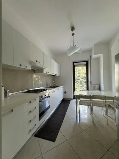 White cabinets stove sink and dining table kitchen at Neat single bedroom in the heart of Verona in Verona Student Accommodation