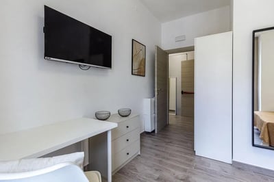 Desk television dresser and art study area at Double Ensuite Bedroom in a 6-bedroom flat near Vanni Stadium in Sassari Student Accommodation