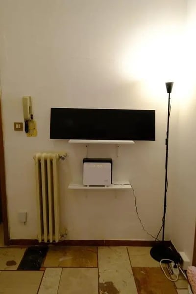 TV on shelf radiator and floor lamp living room at Delightful double bedroom in the heart of Sassari in Sassari Student Accommodation