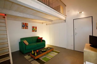 Green sofa with artwork and ladder living room at Chic Studio with Mezzanine in Parioli, Rome | Wi-Fi and Central Heating Included in Rome Student Accommodation