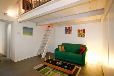Green sofa stairs artwork loft area living room at Chic Studio with Mezzanine in Parioli, Rome | Wi-Fi and Central Heating Included in Rome Student Accommodation