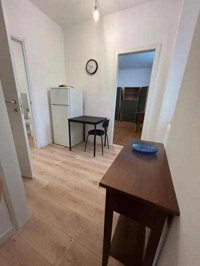 Refrigerator table chairs clock console kitchen at Minimalist one-bedroom apartment in the center of Bergamo: quiet, bright, and with utilities included in Bergamo Student Accommodation
