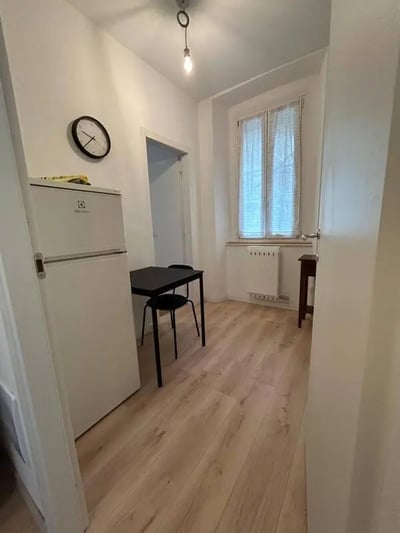 Refrigerator table chairs clock window kitchen at Minimalist one-bedroom apartment in the center of Bergamo: quiet, bright, and with utilities included in Bergamo Student Accommodation