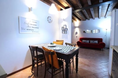 Dining table chairs red sofa living area at Inviting double bedroom near Università Cattolica del Sacro Cuore in Brescia Student Accommodation