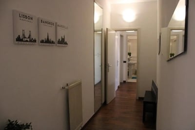 Hallway with art prints radiator and bench hallway at Homely single bedroom near Facoltà di Medicina e Chirurgia in Brescia Student Accommodation