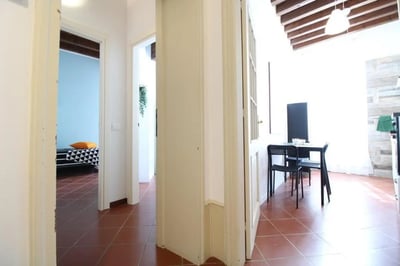 Bed with orange pillow small table and chairs living room at Sublime single bedroom near Università Cattolica del Sacro Cuore in Brescia Student Accommodation