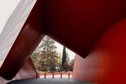 Red architectural structure with trees and sky exterior at Canberra Student Accommodation