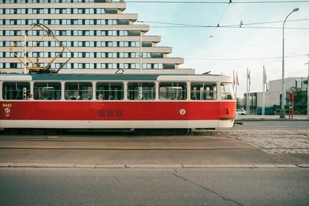 Red and white tram passing modern building exterior