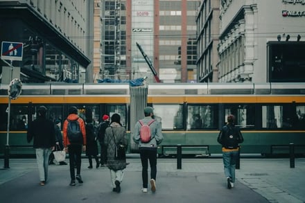Pedestrians walk past a tram in a city exterior