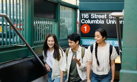 Three students walk up subway stairs exterior